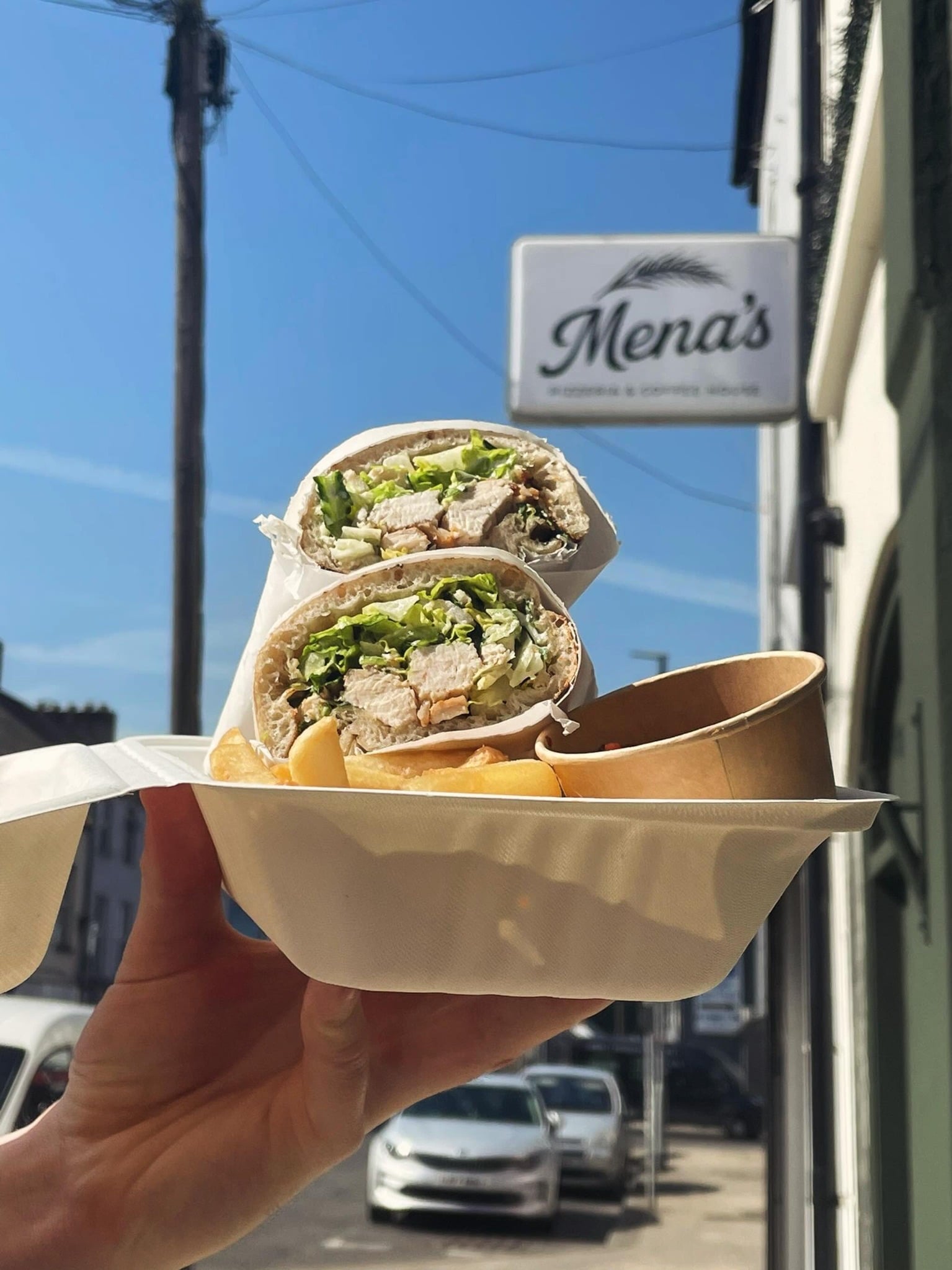 A takeaway wrap and chips photographed outside Mena’s