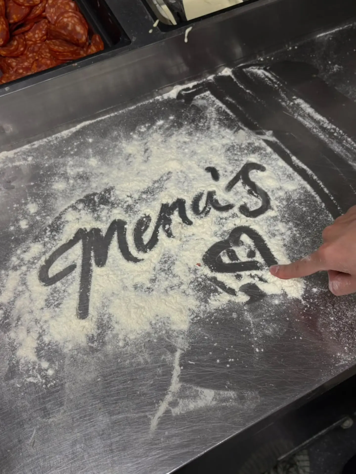 Mena’s name written in flour on the preparation counter