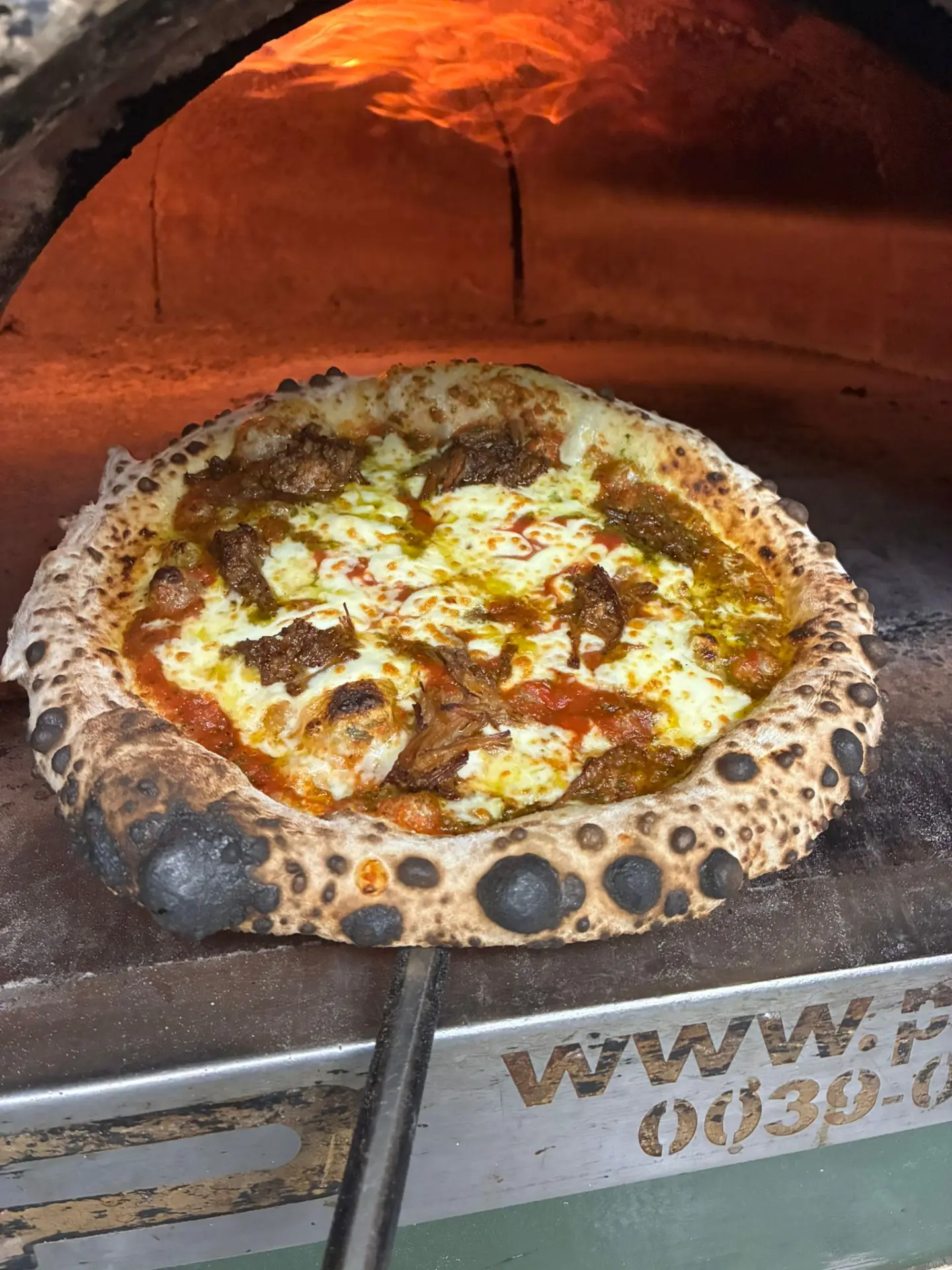 Pizza cooking inside the Mena’s wood-fired oven